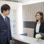 受付で笑顔の対応を受けるスーツ姿の営業マン｜法人向け飛び込み営業シーン