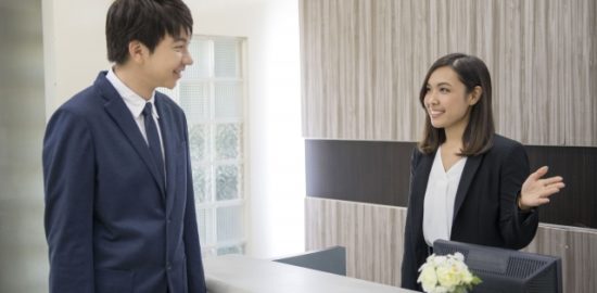 受付で笑顔の対応を受けるスーツ姿の営業マン｜法人向け飛び込み営業シーン